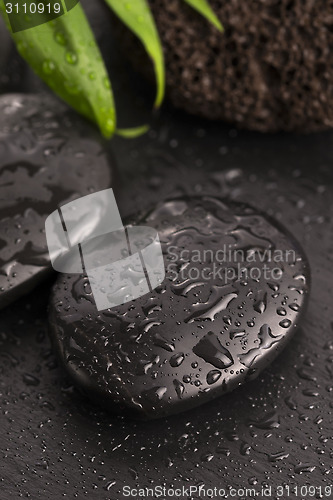 Image of Green leaf on spa stone on wet black surface