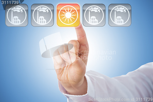 Image of Finger Activating Yellow Solar Energy Icon On Blue