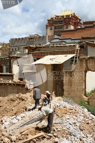 Image of Men working with Tibetan temple in the background