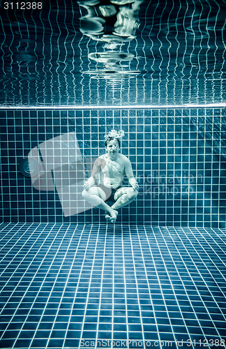 Image of Man under water in a swimming pool to relax in the lotus positio