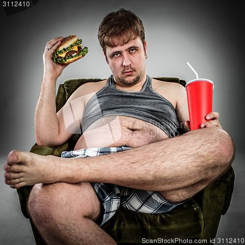 Image of Fat man eating hamburger