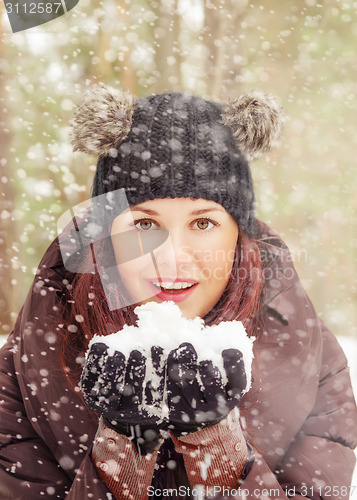 Image of Cute young woman playing with snow  outdoors