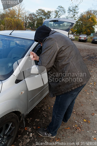 Image of Hooligan breaking into car