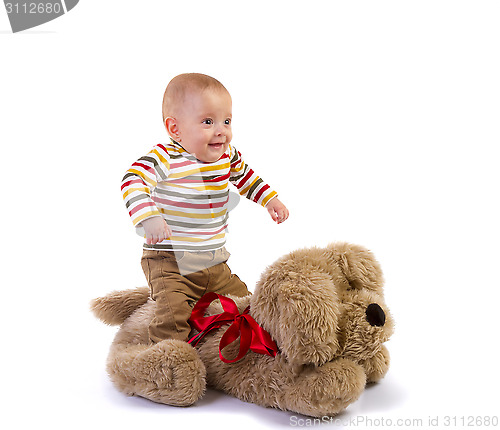 Image of baby boy jump over plush dog