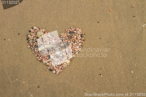 Image of Heart made of sea shells lying on a beach sand