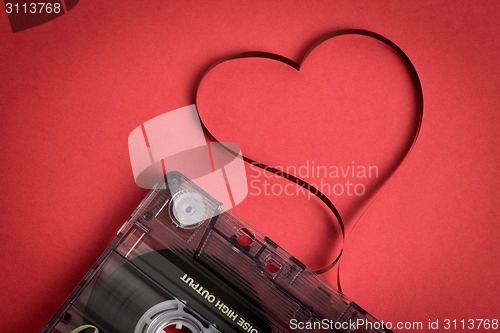 Image of Audio cassette tape on red backgound. Film shaping heart