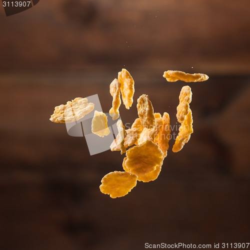 Image of Falling corn flakes on wooden background