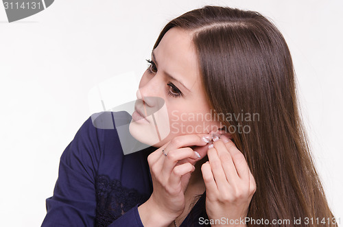 Image of Portrait of a pretty girl corrects an earring in his ear