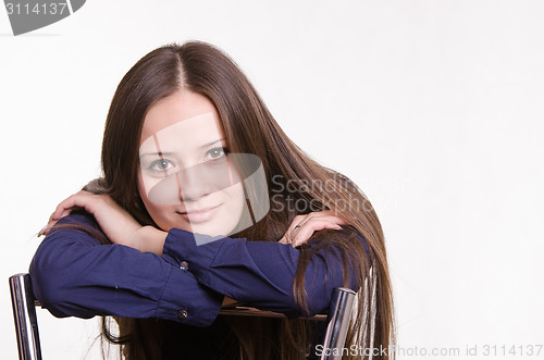 Image of Girl rests on a chair folded hands