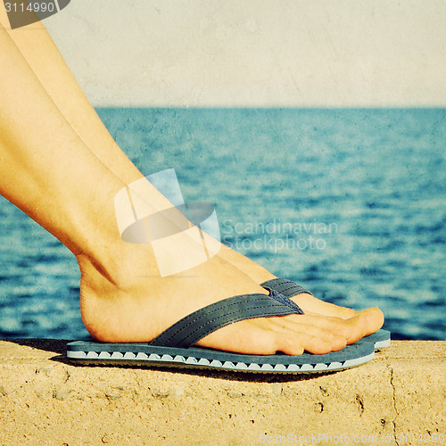 Image of Female feet in blue flip-flops, retro image