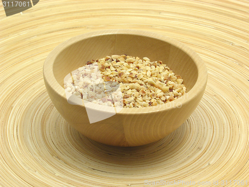 Image of Wooden bowl with roasted hazelnuts on bamboo plate