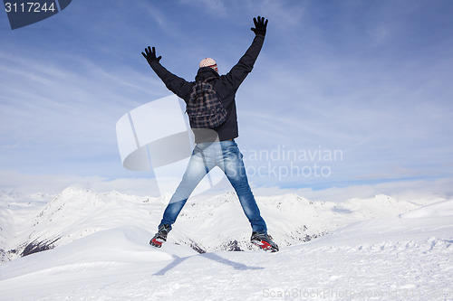 Image of Young man jumps for joy in the snowy mountains