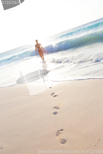 Image of Woman running on the beach in sunset.