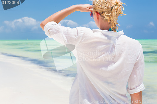 Image of Woman on the beach in white shirt. 