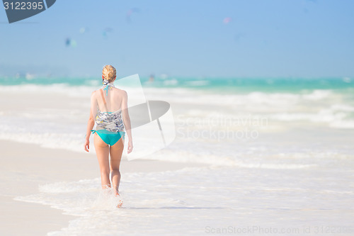 Image of Woman running on the beach in sunset.