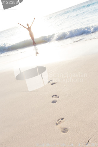 Image of Woman running on the beach in sunset.