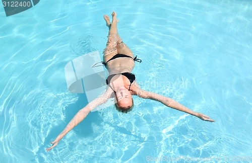 Image of Beautiful Caucasian lady floating in swimming pool.