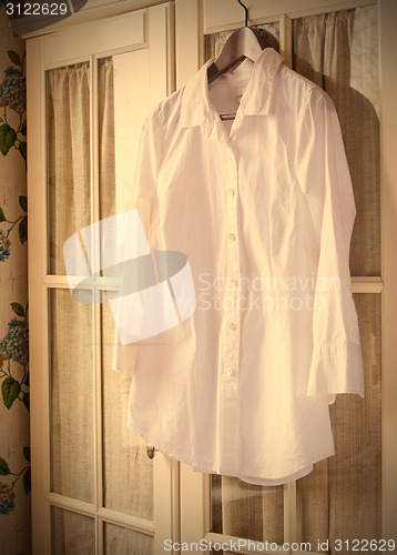 Image of white cotton shirt on a hanger