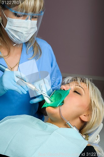 Image of dentist with patient, using dental curing light