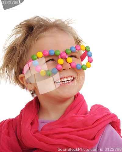 Image of Portrait of cute little girl wearing funny glasses, decorated with colorful sweets, smarties, candies