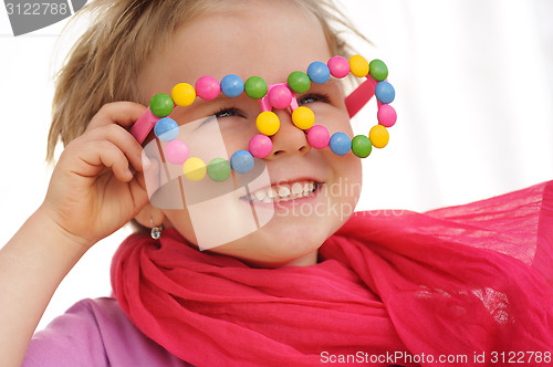 Image of Portrait of cute little girl wearing funny glasses, decorated with colorful sweets, smarties, candies