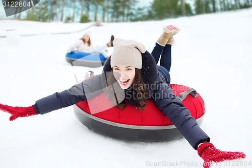 Image of group of happy friends sliding down on snow tubes