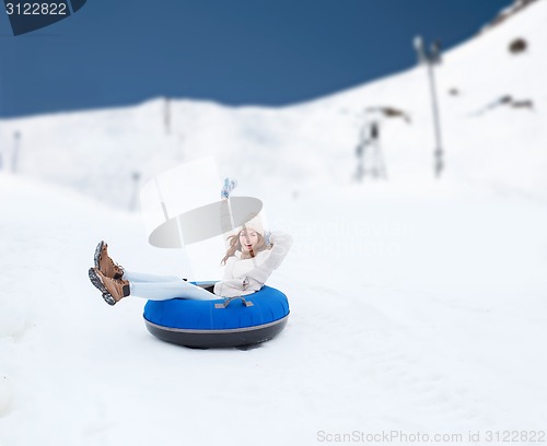 Image of happy teenage girl sliding down on snow tube