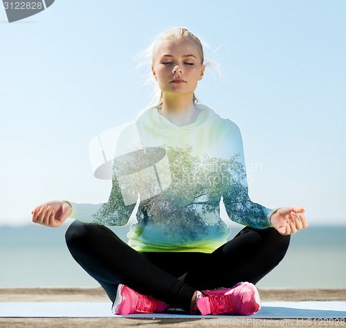 Image of happy young woman doing yoga outdoors