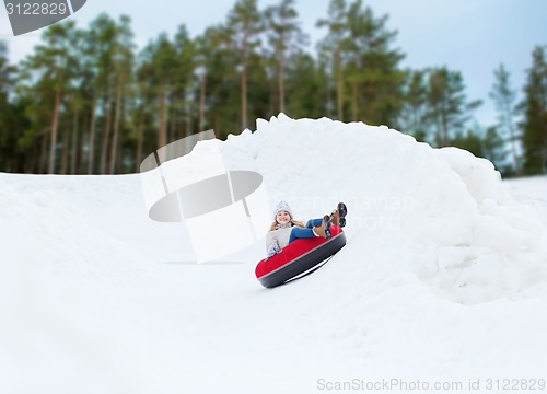 Image of happy teenage girl sliding down on snow tube