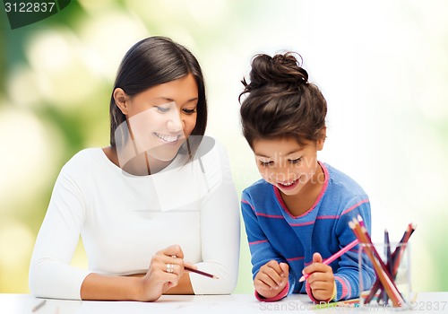 Image of happy mother and daughter drawing with pencils