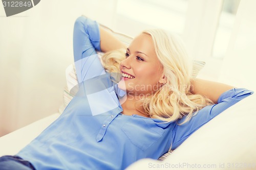 Image of smiling young woman lying on sofa at home