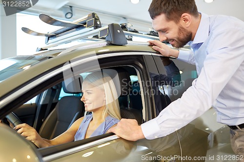 Image of happy couple buying car in auto show or salon