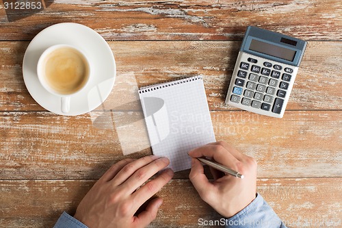 Image of close up of hands with calculator and notebook