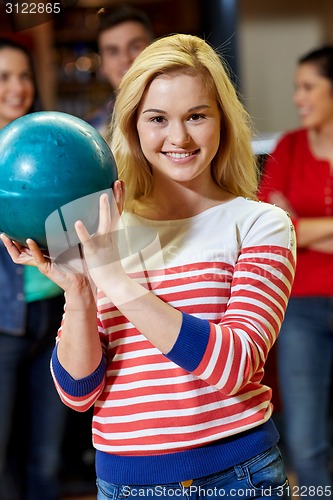 Image of happy young woman holding ball in bowling club