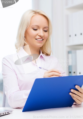 Image of smiling businesswoman with clipboard in office