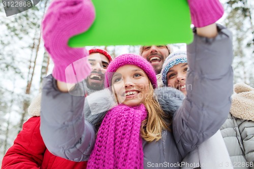 Image of smiling friends with tablet pc in winter forest