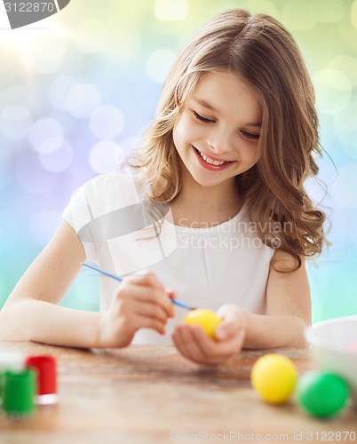 Image of happy girl with brush coloring easter eggs