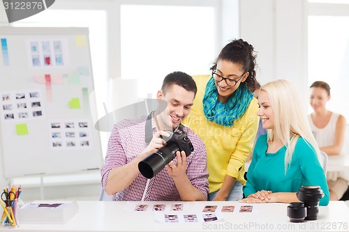 Image of smiling team with photocamera working in office