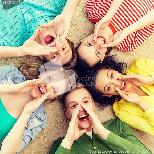 Image of smiling people lying down on floor and screaming