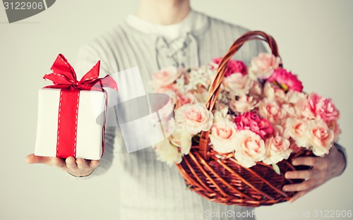 Image of man holding basket full of flowers and gift box