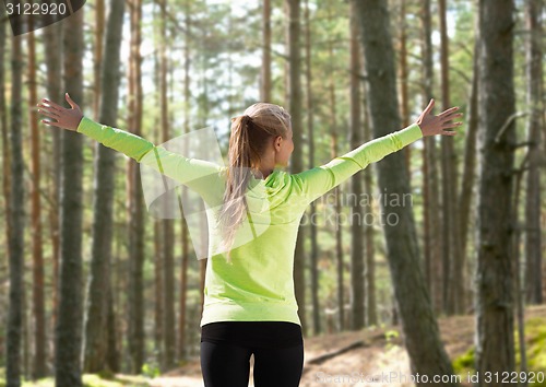 Image of happy woman in sport clothes raising hands