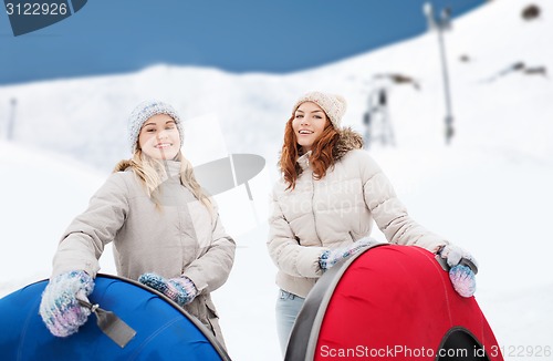 Image of happy girl friends with snow tubes outdoors