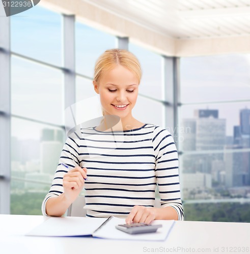 Image of happy woman with notebook and calculator