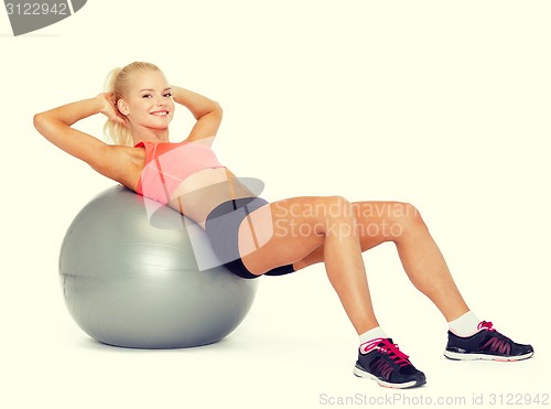 Image of smiling sporty woman exercising on fitness ball