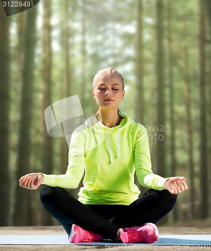 Image of happy young woman doing yoga outdoors