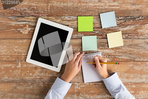 Image of close up of hands with tablet pc and notebook