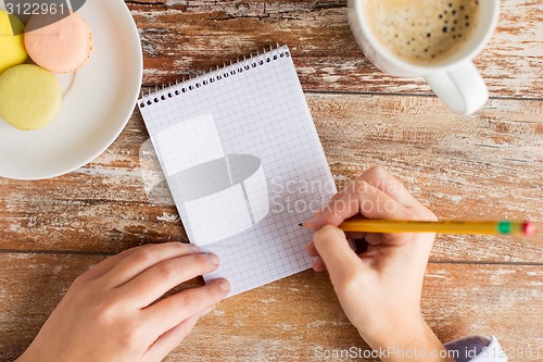 Image of close up of hands, notebook, coffee and cookies