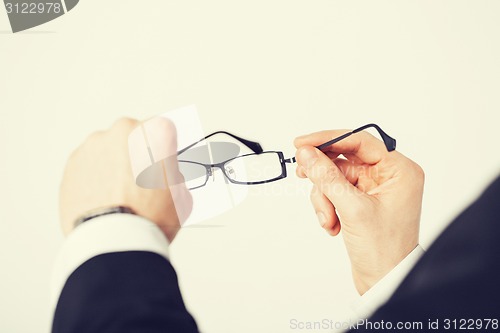 Image of man hands holding eyeglasses