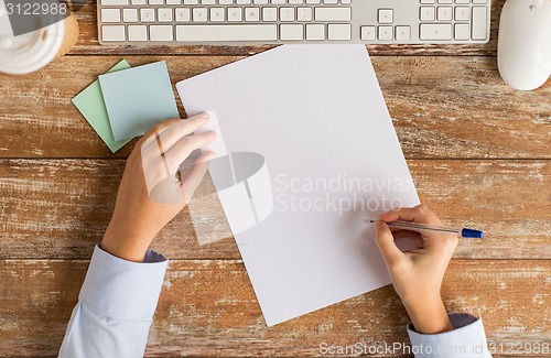 Image of close up of hands with paper sheet and keyboard