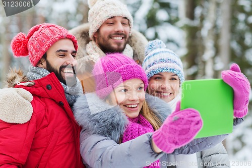 Image of smiling friends with tablet pc in winter forest